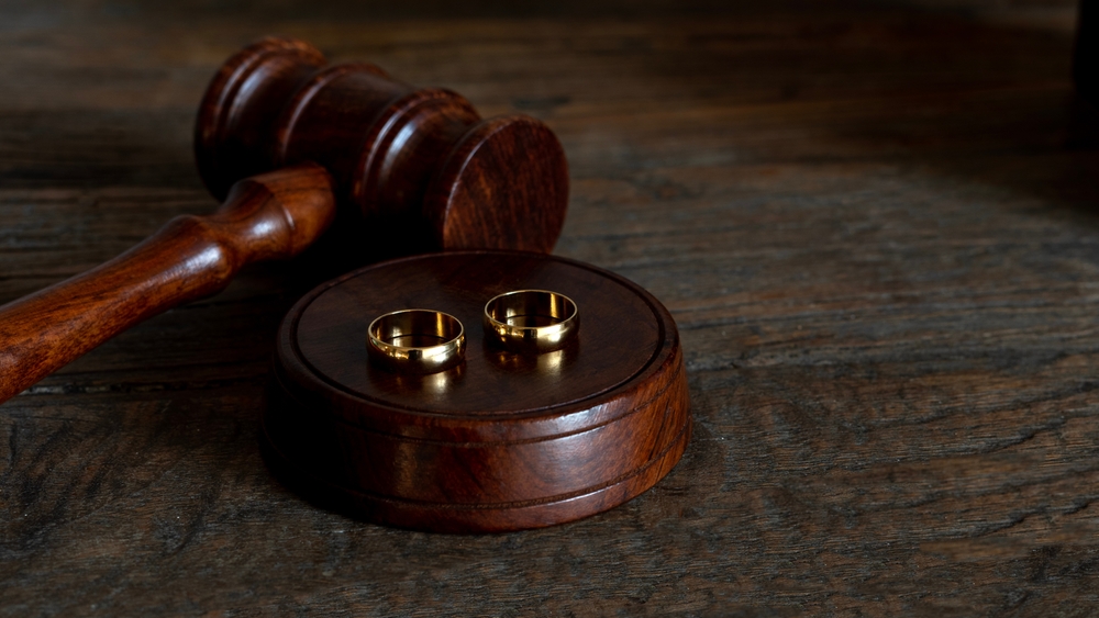 Wedding rings placed beside a judge’s gavel symbolizing the divorce process