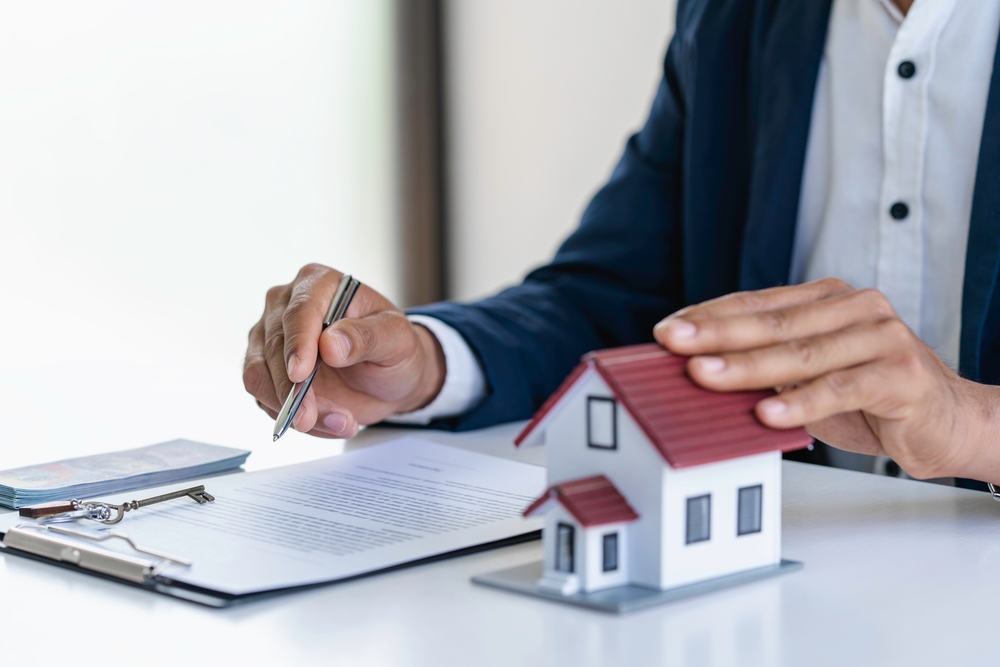Person reviewing estate planning documents beside a model house